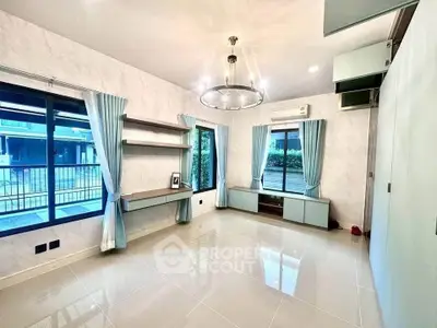 Spacious living room with modern chandelier and large windows offering natural light.