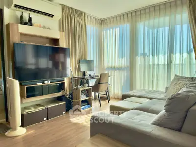 Spacious living room with modern decor, large TV, and ample natural light from floor-to-ceiling windows.
