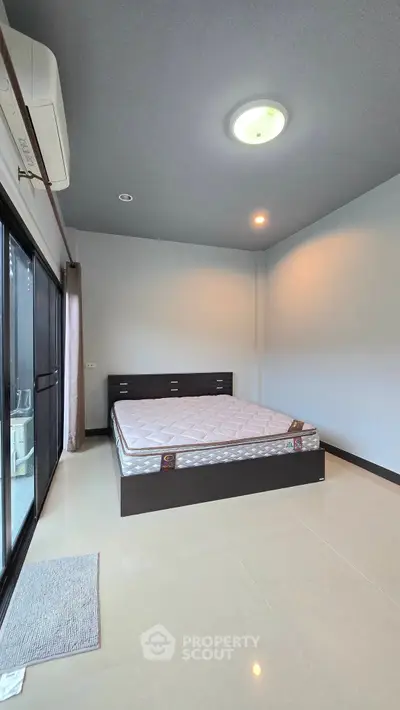 Spacious bedroom with large window and modern bed frame, perfect for relaxation and comfort.