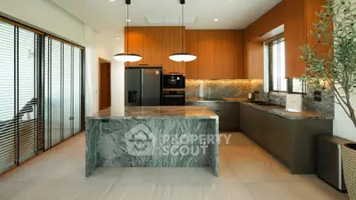 Luxurious modern kitchen with marble island and wooden cabinetry, featuring sleek appliances and elegant lighting.