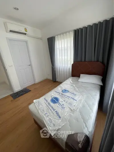 Cozy bedroom with single bed, wooden flooring, and air conditioning in modern apartment.