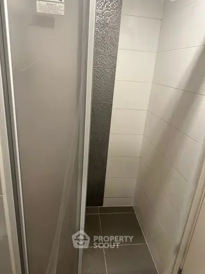 Modern shower area with sleek tiles and glass door in a contemporary bathroom.