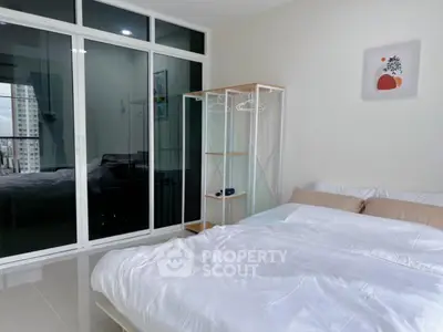Modern bedroom with large glass doors and minimalist decor in a high-rise apartment.