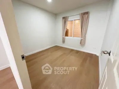 Spacious empty room with wooden flooring and window view