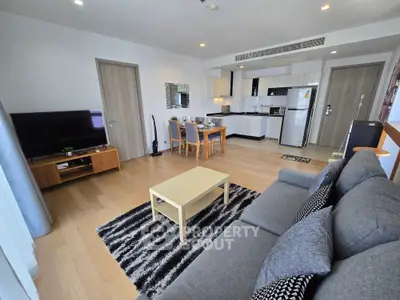 Spacious modern living room with open kitchen, featuring stylish furniture and sleek appliances.
