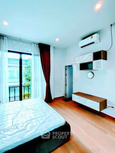 Modern bedroom with large window and air conditioning, featuring sleek furniture and natural light.