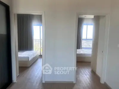Modern apartment with two bright bedrooms featuring large windows and wooden flooring.