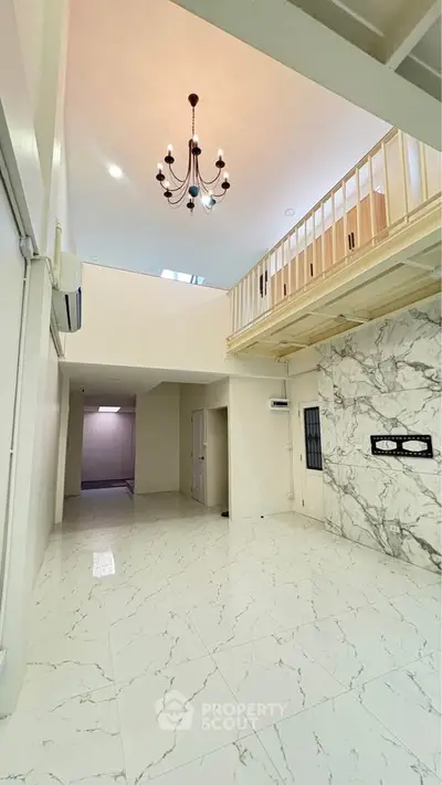 Spacious modern interior with high ceilings and elegant chandelier in a stylish open layout.