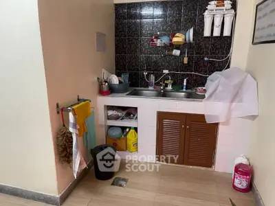 Compact kitchen with dual sink and storage, featuring a tiled backsplash and water filtration system.