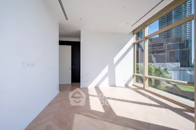 Spacious sunlit room with large windows and city view, perfect for modern living.