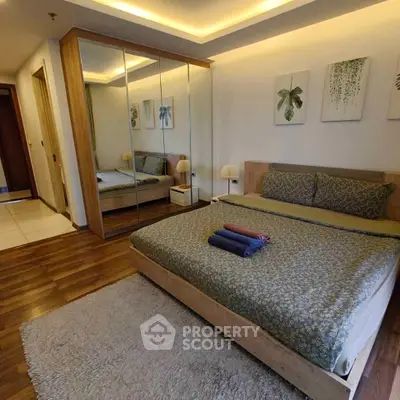 Spacious bedroom with mirrored wardrobe and cozy decor in modern apartment.