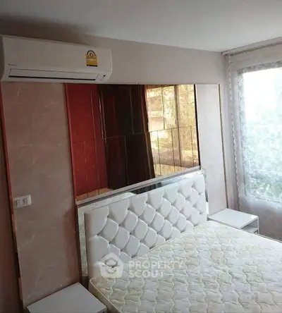 Modern bedroom with stylish padded headboard and large window for natural light.