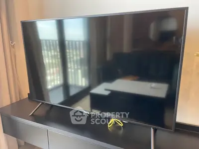 Modern living room with sleek flat-screen TV and balcony view, perfect for urban living.