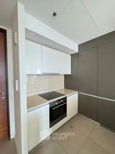 Modern kitchen with sleek cabinetry and built-in oven in contemporary apartment.