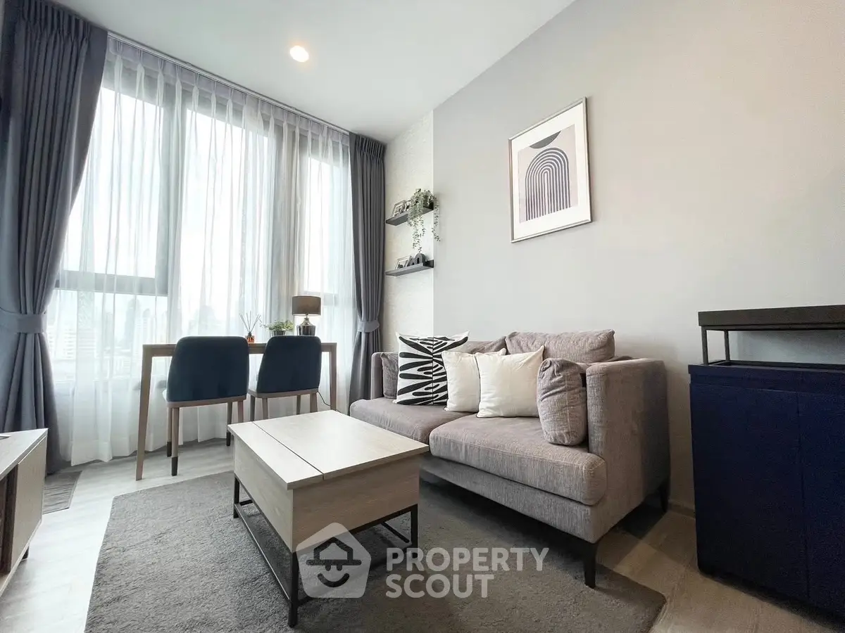 Modern living room with stylish decor and large window offering natural light.
