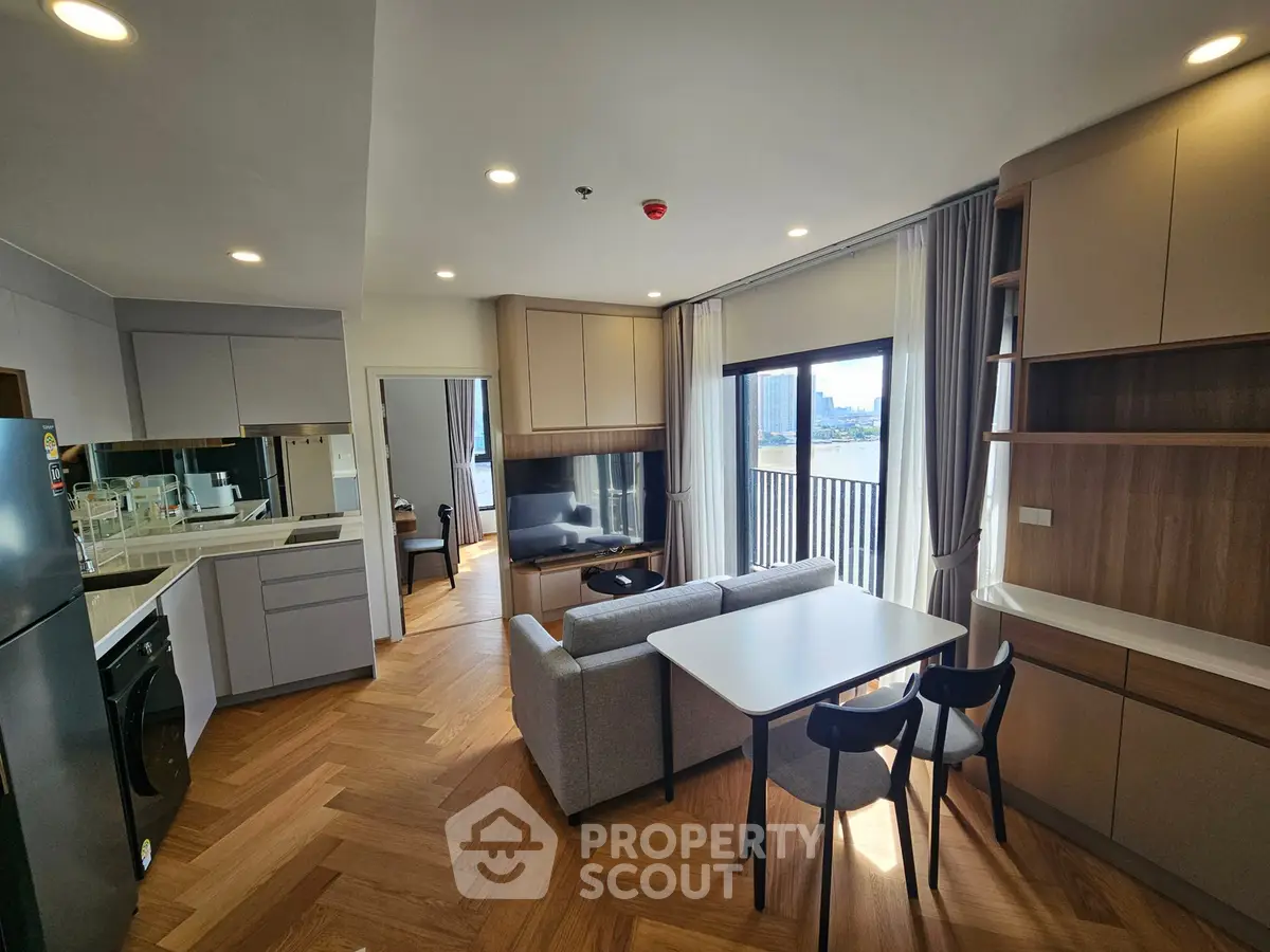 Modern open-layout living room with kitchen, featuring sleek design and city view balcony.