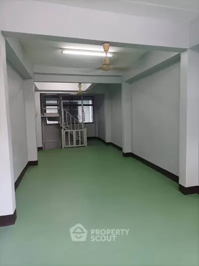 Spacious interior with green flooring and ceiling fans, ideal for versatile use.