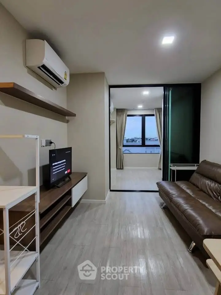 Modern living room with sleek design and city view, featuring a comfortable sofa and entertainment setup.