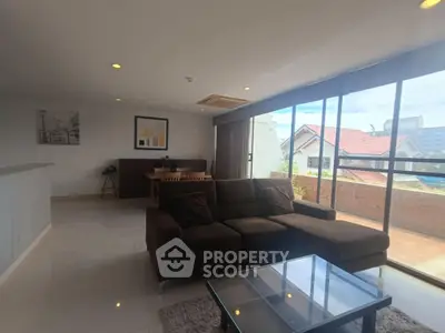 Spacious living room with large windows and balcony view, modern furniture, and natural light.