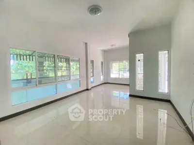 Spacious empty living room with large windows and glossy tiled floor