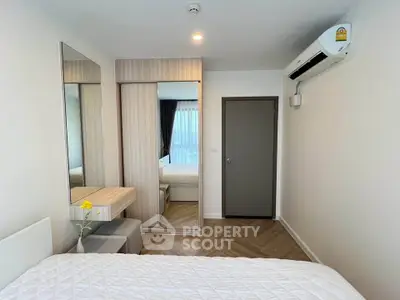 Modern bedroom with sleek design, featuring a large mirror, built-in wardrobe, and air conditioning.
