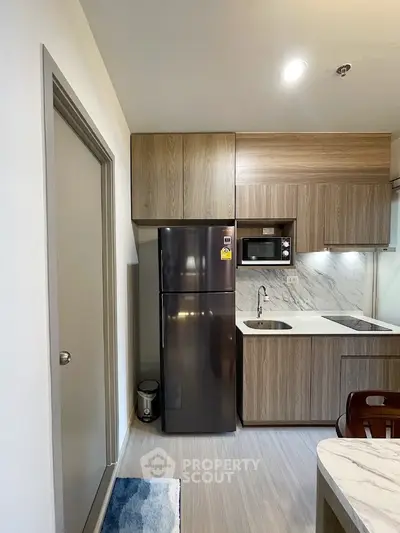Modern kitchen with sleek appliances and wood cabinetry in a compact layout.