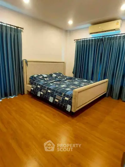 Spacious bedroom with elegant wooden flooring and modern blue curtains