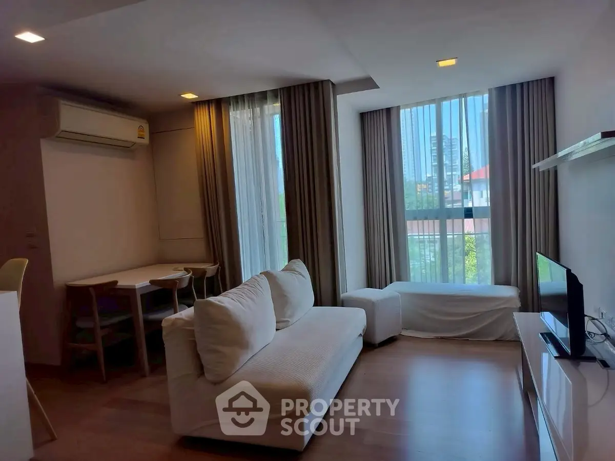 Modern living room with large windows and cozy furniture in a stylish apartment.