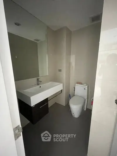 Modern bathroom with sleek fixtures and minimalist design, featuring a spacious sink and contemporary toilet.