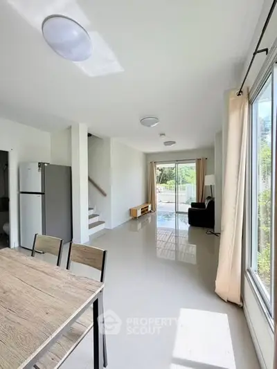 Spacious open-plan living area with large windows and modern furnishings, offering a bright and airy atmosphere.