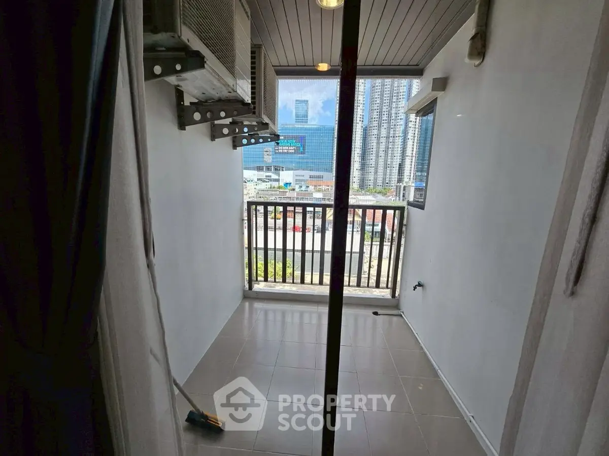 Compact balcony with city view, ideal for urban living, featuring air conditioning units and tiled flooring.