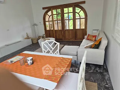 Charming living room with elegant decor and large wooden doors opening to a lush garden view.
