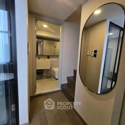 Modern hallway with mirror leading to a sleek bathroom in a contemporary apartment.