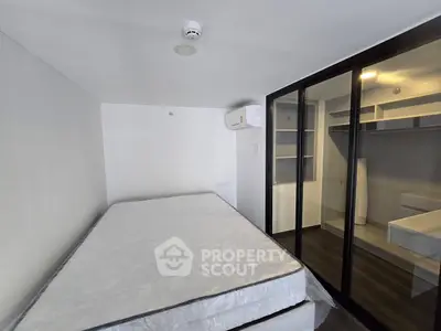 Modern bedroom with sliding glass closet doors and air conditioning in a minimalist apartment.