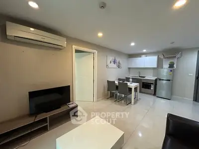 Modern living room with open kitchen, featuring sleek furniture and contemporary design.