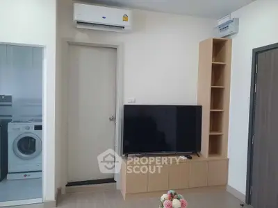 Modern living room with TV, air conditioning, and washing machine in view.