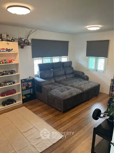 Cozy living room with plush gray sofa and wooden flooring, perfect for relaxation and entertainment.