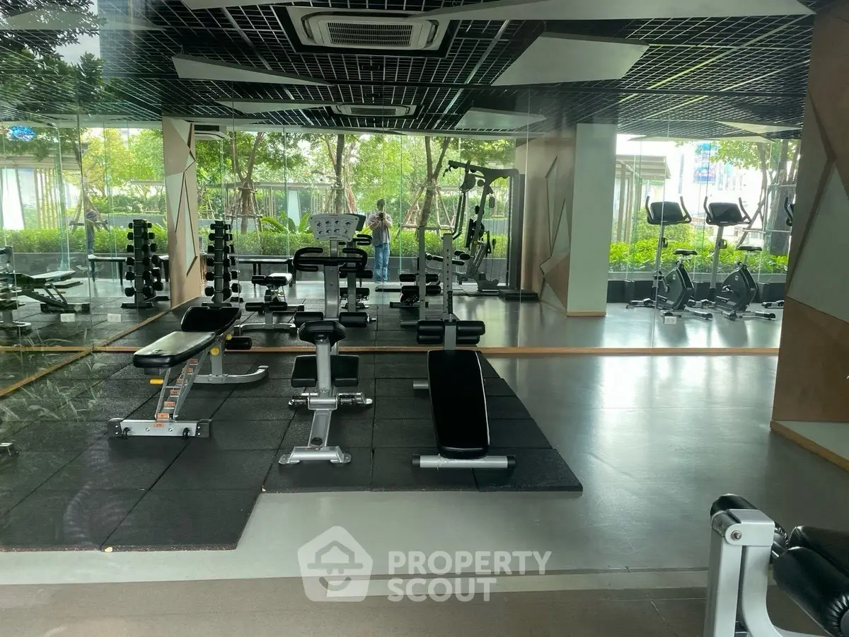 Modern gym with state-of-the-art equipment and lush garden view, perfect for fitness enthusiasts.