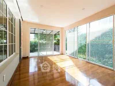 Spacious sunlit room with large windows and garden view, perfect for modern living.