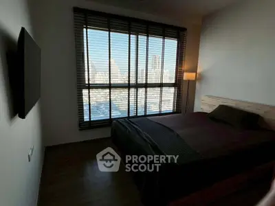 Modern bedroom with large window offering city skyline view