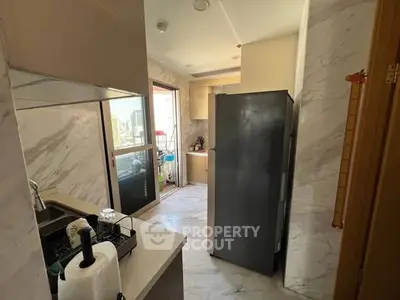 Modern kitchen with sleek design and marble accents, featuring a large refrigerator and ample natural light.