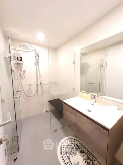 Modern bathroom with glass shower enclosure and sleek vanity in a contemporary apartment.