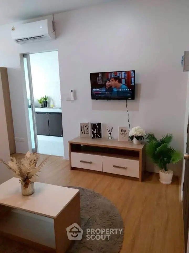 Modern living room with wall-mounted TV and stylish decor in a cozy apartment.