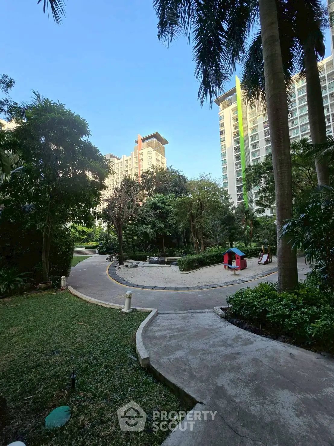 Lush garden view with modern high-rise buildings and walking path
