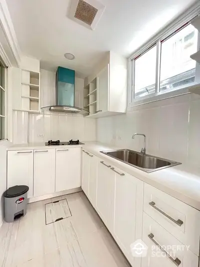 Modern white kitchen with gas stove and ample storage space