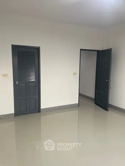 Spacious empty room with sleek gray doors and glossy tiled floor