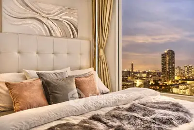 Luxurious bedroom with stunning city skyline view, plush bedding, and elegant decor.