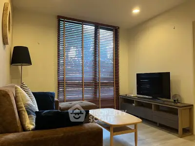 Cozy living room with modern decor, featuring a comfortable sofa, stylish blinds, and a flat-screen TV.