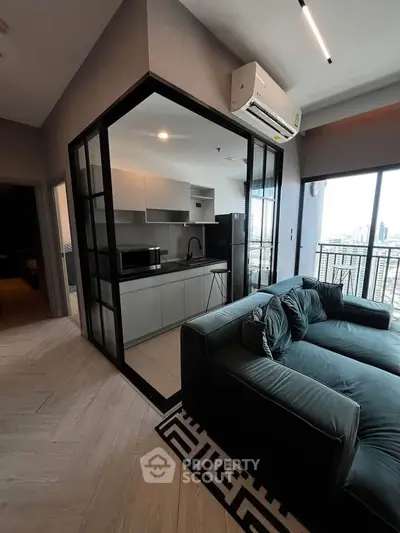 Modern living room with sleek kitchen and city view balcony, featuring stylish furniture and air conditioning.