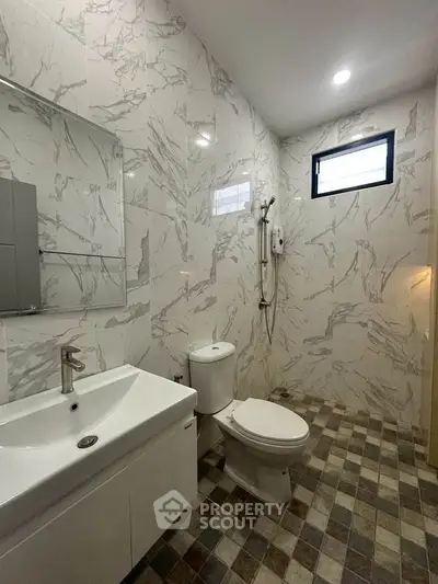 Modern bathroom with marble tiles and sleek fixtures, featuring a shower and vanity.